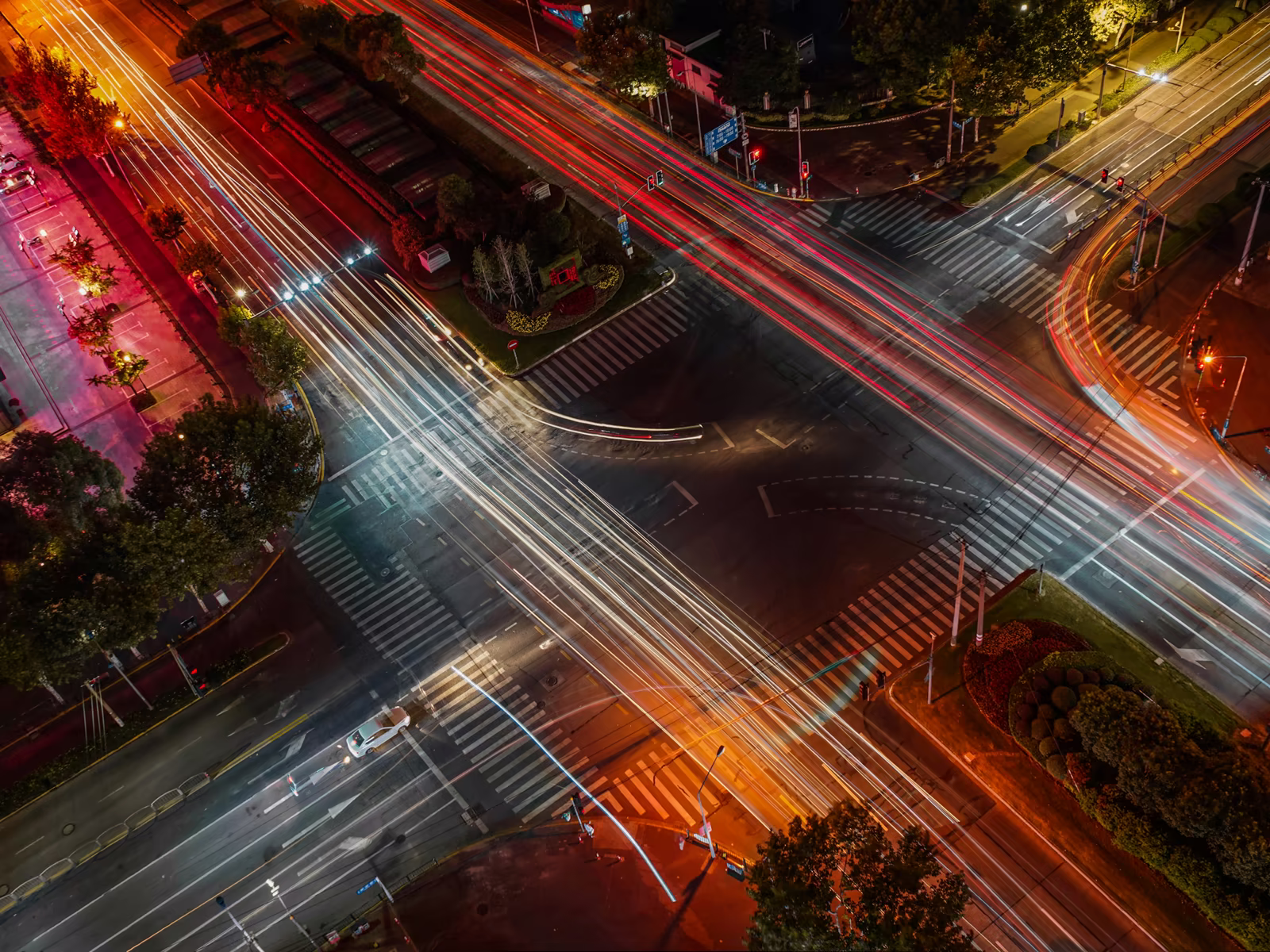 City roads crossing at night, traced by streams of moving light